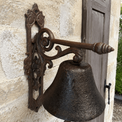 Detail der klassischen Türglocke mit geschwungenen Voluten, dekorativer Spitze und großer Glocke