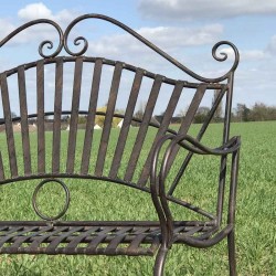 Nahaufnahme einer schmiedeeisernen Gartenbank mit Arabesken