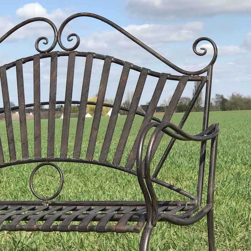 Nahaufnahme einer schmiedeeisernen Gartenbank mit Arabesken