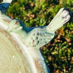 Kleiner Metallvogel auf dem Rand der Vogeltränke