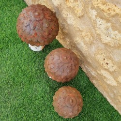 Drei rostfarbene Gartenpilze aus Metall in abgestuften Größen