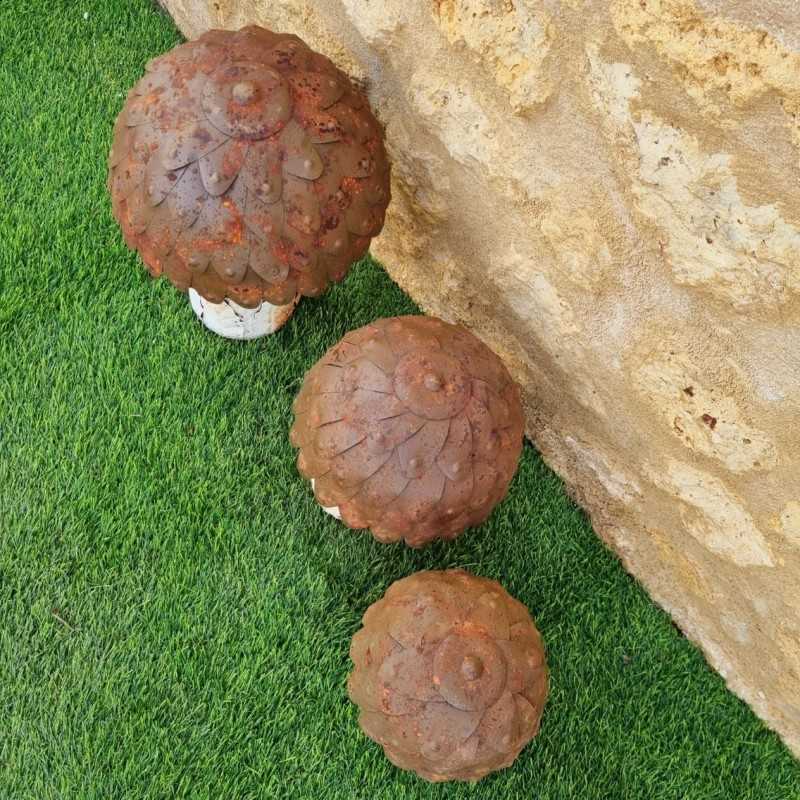 Drei rostfarbene Gartenpilze aus Metall in abgestuften Größen