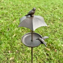 Vogelfutterstelle aus Gusseisen mit Schutzdach und zwei Vögeln
