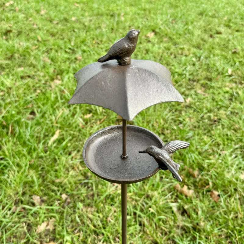 Vogelfutterstelle aus Gusseisen mit Schutzdach und zwei Vögeln