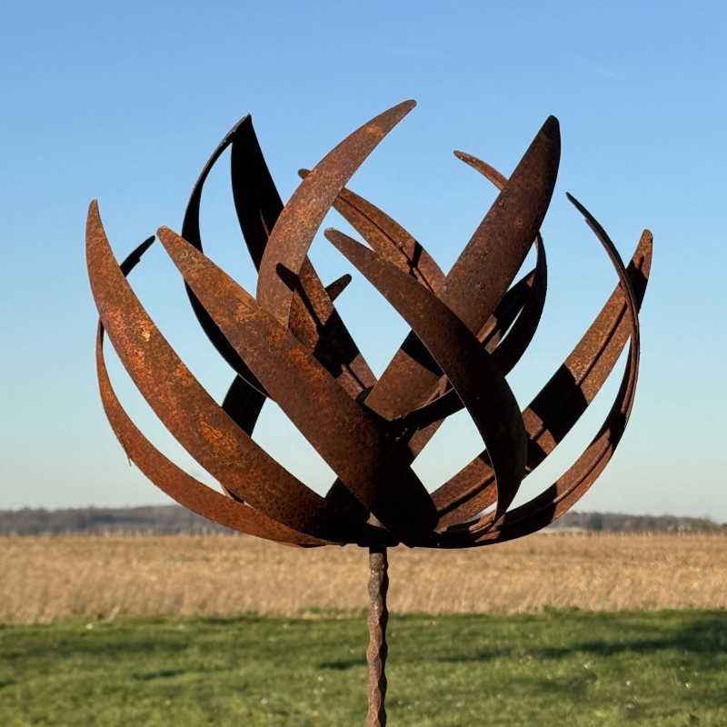 Vollansicht der dekorativen Gartenwindmühle aus rostigem Metall unter klarem Himmel
