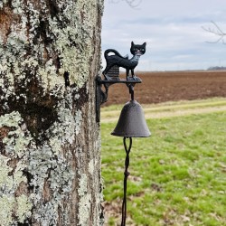 Katzen-Türglocke aus Gusseisen neben einer hölzernen Eingangstür