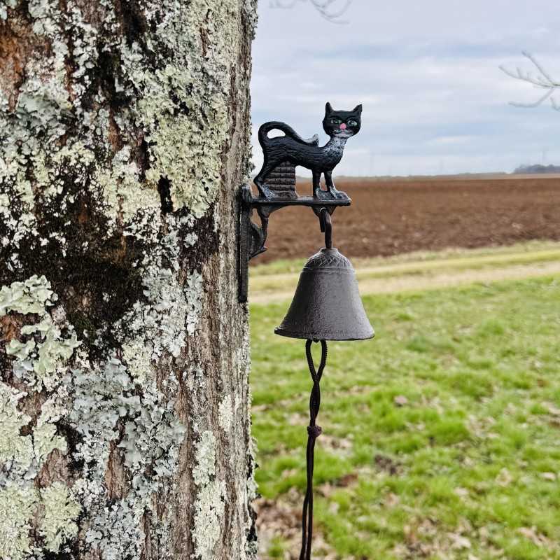 Katzen-Türglocke aus Gusseisen neben einer hölzernen Eingangstür