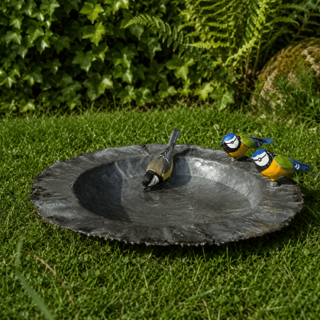 Schwarze Vogeltränke aus recyceltem Metall mit zwei bunten Meisen