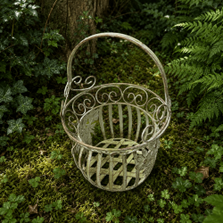 Dekorativer Metallkorb für Blumentöpfe mit salbeigrüner Vintage-Patina in einer natürlichen Gartenecke