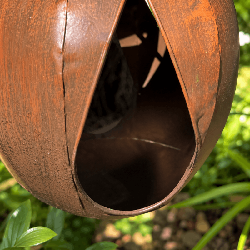 Hängendes Vogelhaus aus Metall in Eichelform mit buntem Vogel