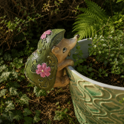 Grüner Igel-Topfhänger mit rosa Blumen an einem Keramiktopf